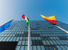 Modern glass and steel skyscraper against a blue sky, with the European, German and NRW flags.